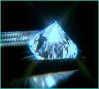 A cut diamond held by tongs