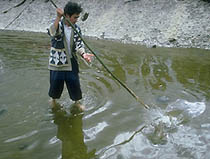 An Ainu man fishing using a traditional technique