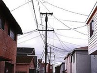 Photo of telephone and electric wires strung between poles and homes