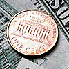 A penny sitting on a U.S. dollar bill.