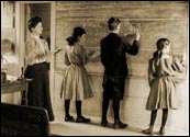 Students in the early 1900s writing at the chalkboard.