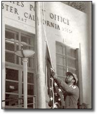 A postal worker raises the American flag in front of a California post office.